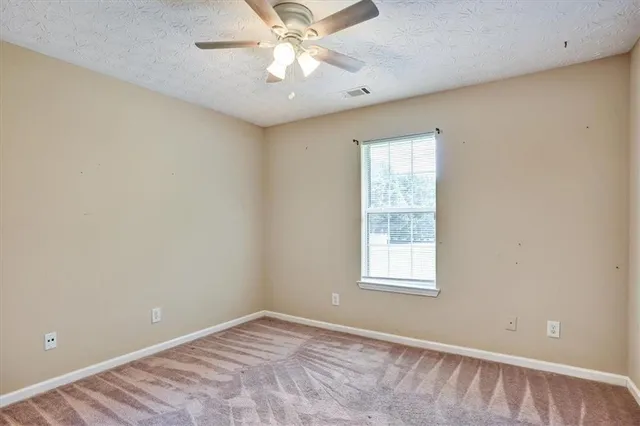an empty room with a window and a fan