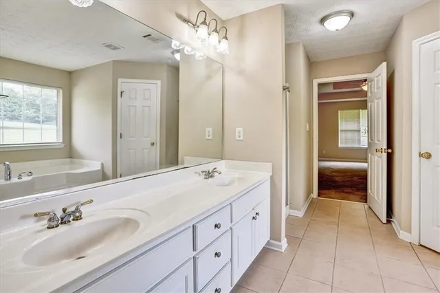 a spacious bathroom with a double vanity sink a large mirror and a shower