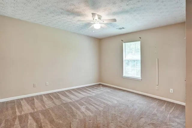 an empty room with a chandelier fan and windows