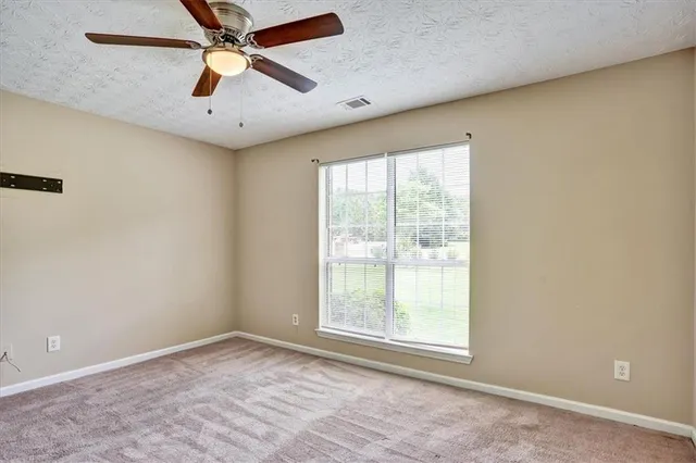 an empty room with a window and a fan