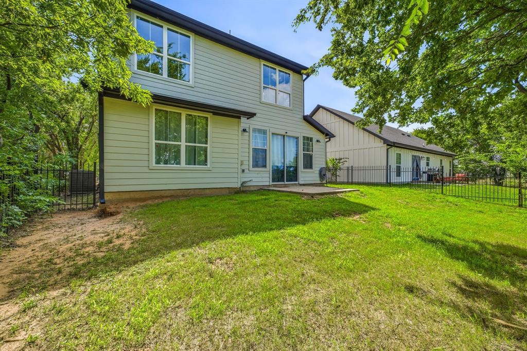 745 North Miller Avenue Stephenville, TX 76401 - Photo 29 of 31 Rear exterior featuring light-colored siding, a black roof, and multiple windows