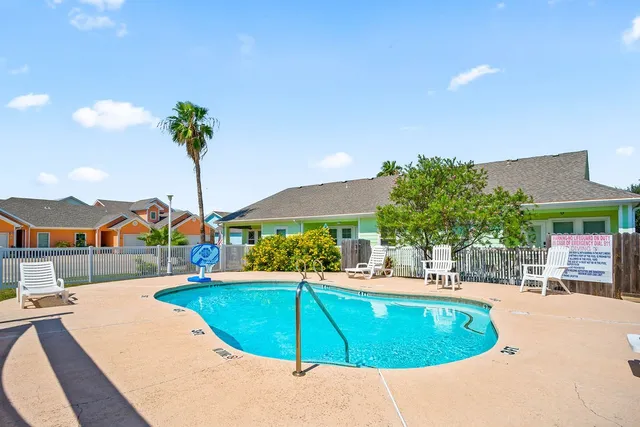 a view of a swimming pool with a lawn chairs under an umbrella