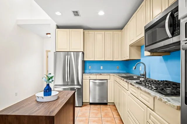 a kitchen with kitchen island granite countertop a sink cabinets and stainless steel appliances