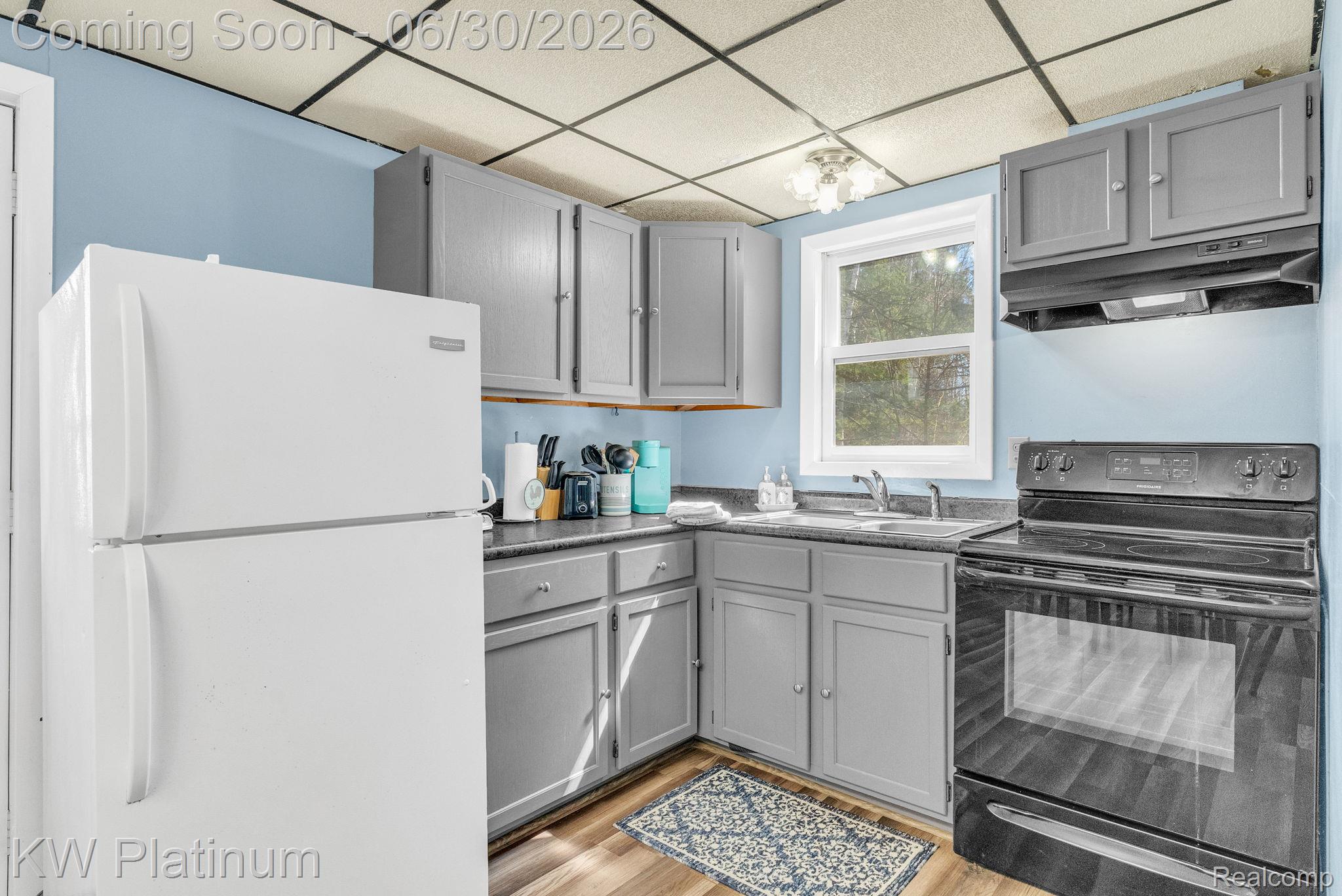 2235 South Lake Shore Road Harbor Beach, MI 48441 - Photo 71 of 99 Kitchen featuring wood-finish flooring, light blue walls, grey cabinetry, a black electric range, and a white top-freezer refrigerator