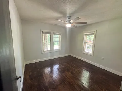 an empty room with wooden floor closet and fan