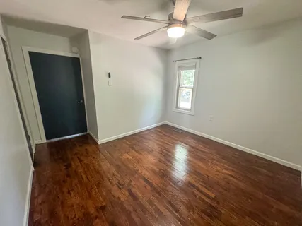 an empty room with wooden floor and fan