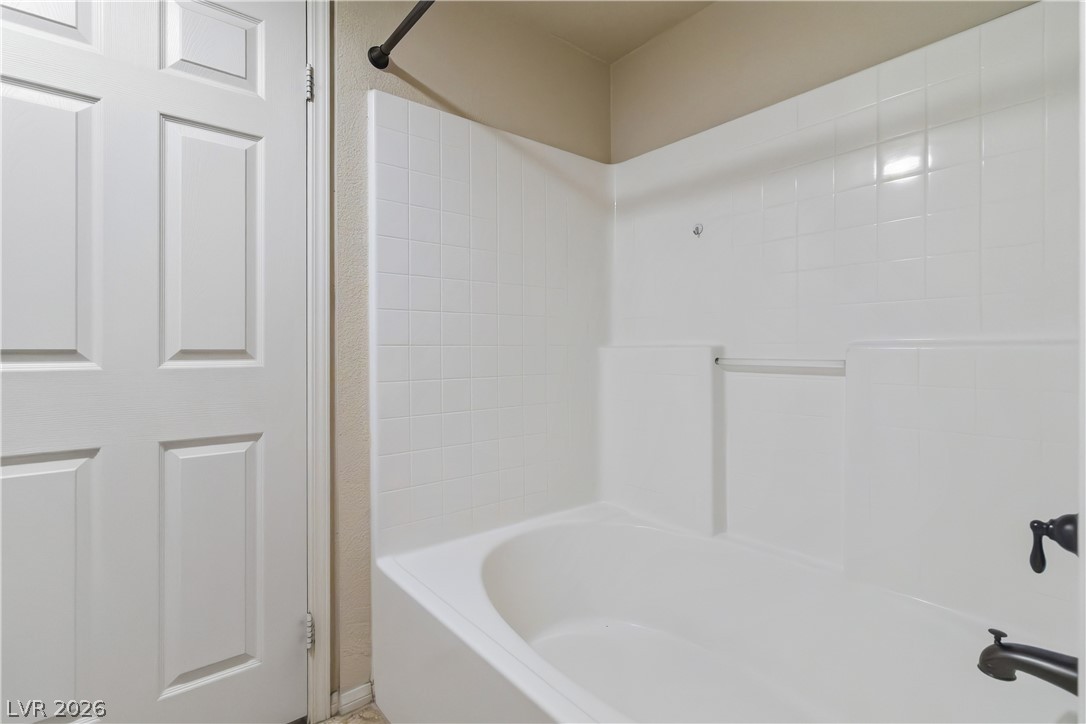 10550 West Alexander Road, Unit 2060 Las Vegas, NV 89129 - Photo 32 of 45 A pristine white tub and shower surround offer a clean, functional bathing space.