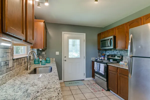 a kitchen with stainless steel appliances granite countertop a refrigerator stove top oven and sink