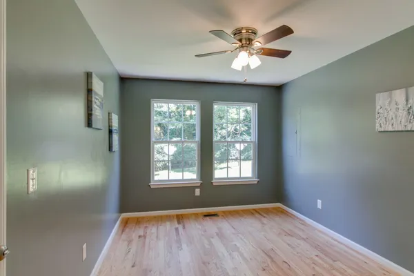 a view of an empty room with window and wooden floor