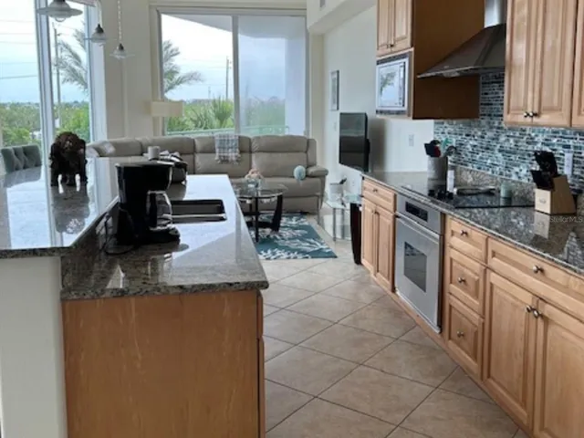 a kitchen with stainless steel appliances granite countertop a sink counter space and a view of living room