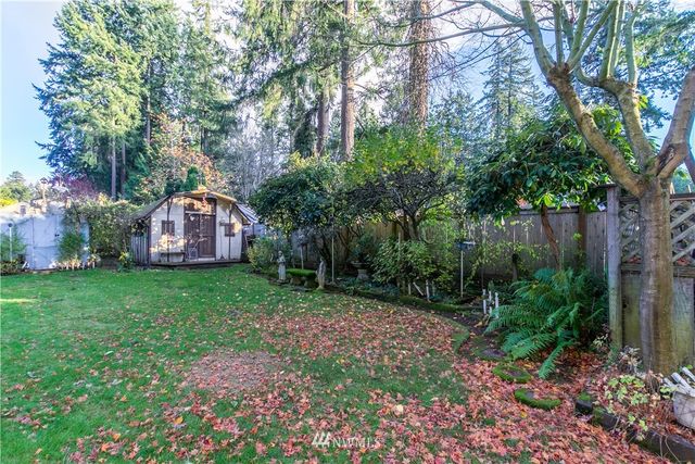 a view of backyard with wooden fence and a large tree