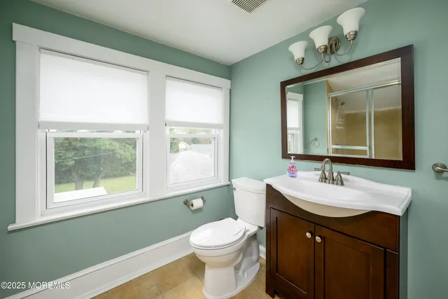 a bathroom with a toilet sink a window and shower