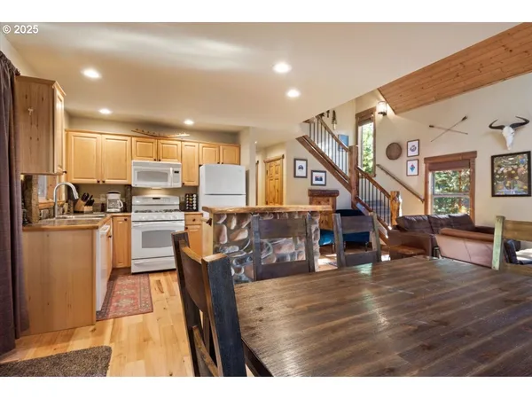 a kitchen with stainless steel appliances kitchen island granite countertop a refrigerator a stove a microwave oven a dining table and chairs with wooden floor