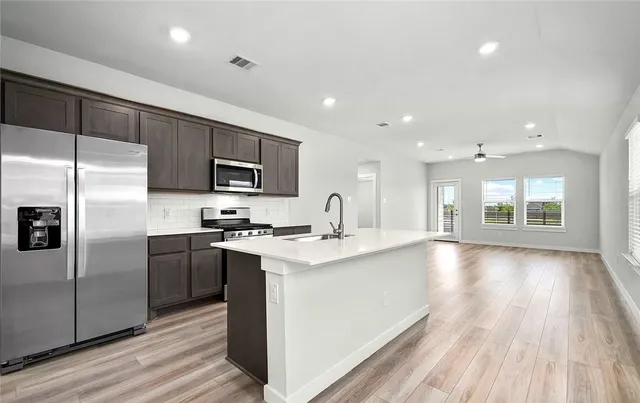 a kitchen with stainless steel appliances granite countertop a stove a sink and a refrigerator