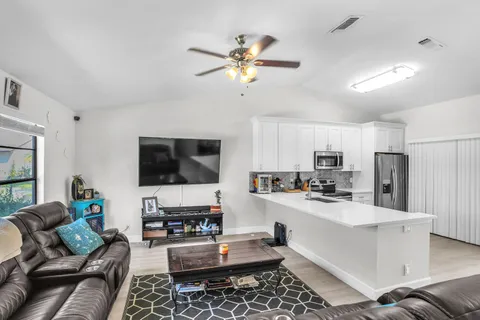 a kitchen with stainless steel appliances granite countertop a stove refrigerator a sink dishwasher a dining table and chairs with wooden floor