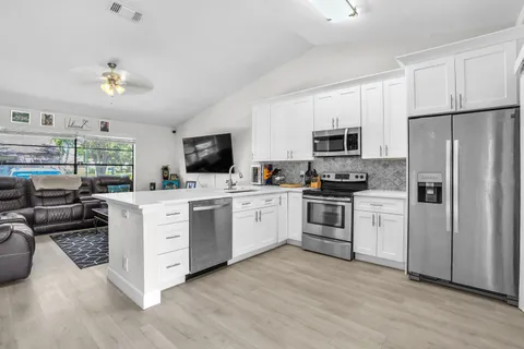 a kitchen with white cabinets stainless steel appliances and wooden floor