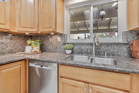 a kitchen with granite countertop a sink and a white wooden cabinets