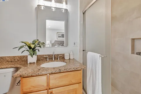a bathroom with a granite countertop sink and a mirror