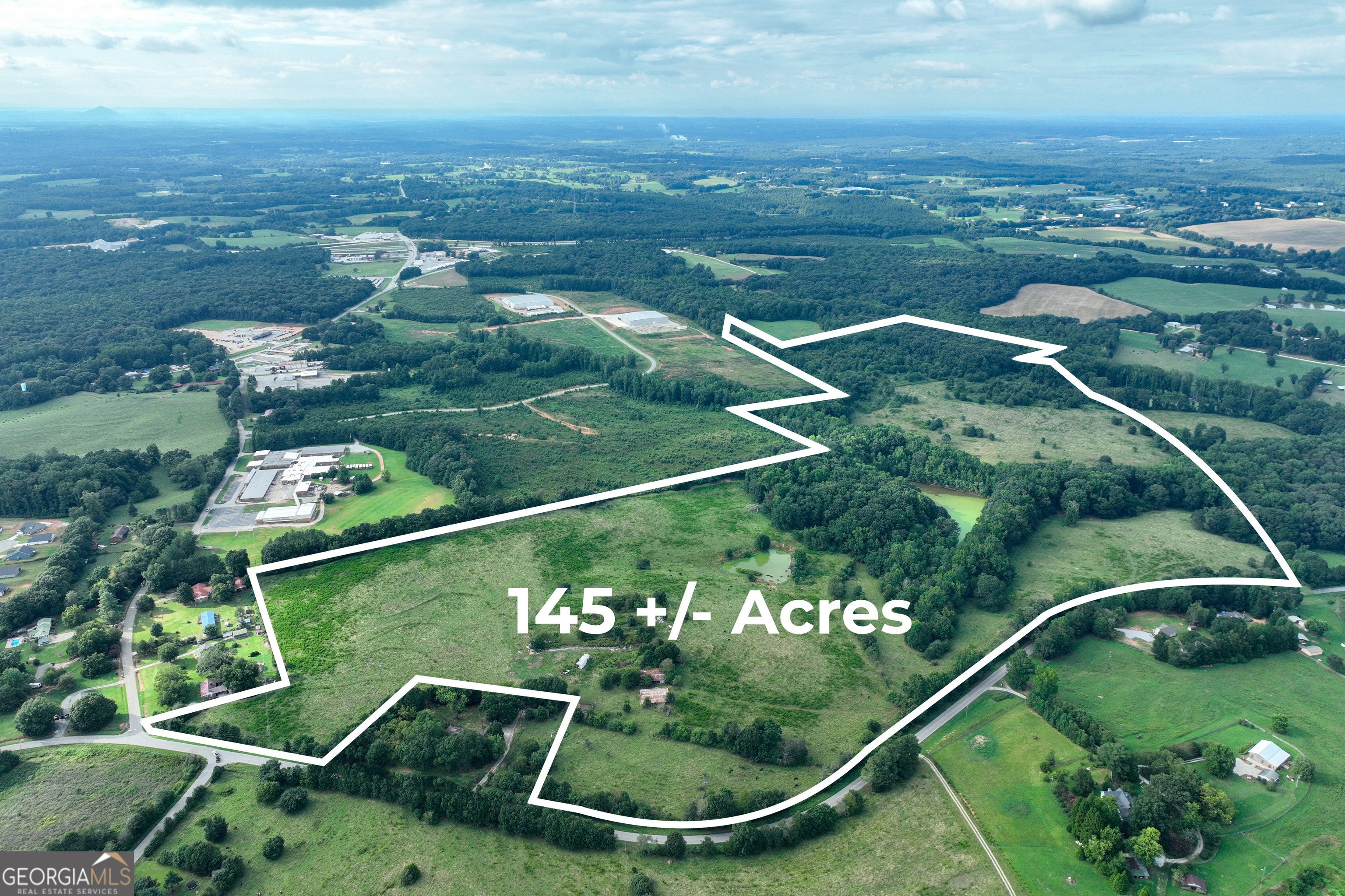 an aerial view of a residential houses with outdoor space and trees