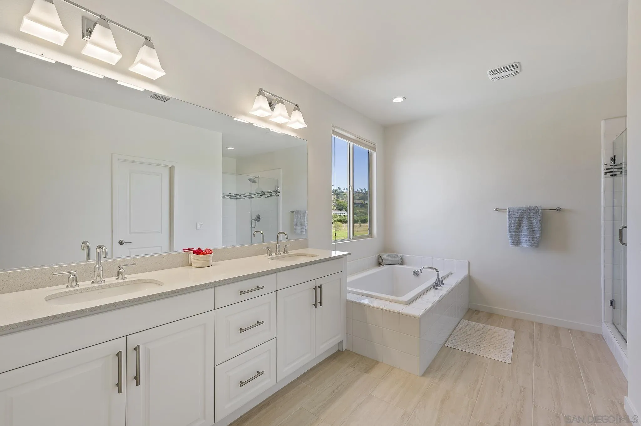 31657 Calle De Las Estrellas Bonsall, CA 92003 - Photo 24 of 30 a bathroom with a double vanity sink a mirror and a bathtub