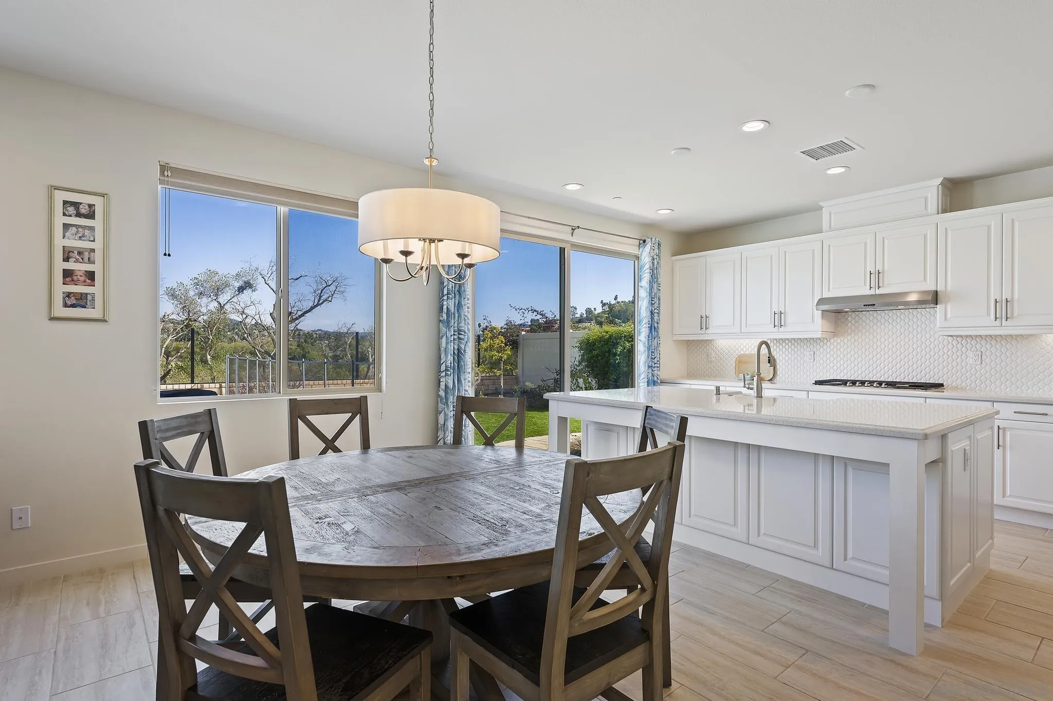 31657 Calle De Las Estrellas Bonsall, CA 92003 - Photo 10 of 30 a kitchen with stainless steel appliances granite countertop a dining table chairs and white cabinets