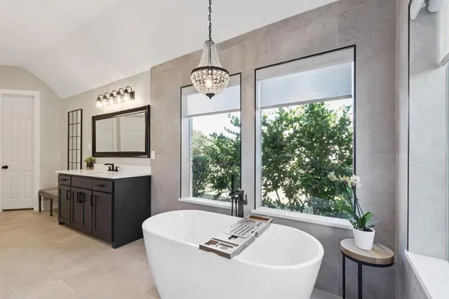 a spacious bathroom with a tub sink and mirror