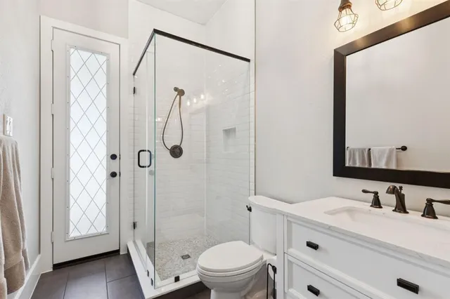 a bathroom with a granite countertop sink toilet a mirror a vanity and shower