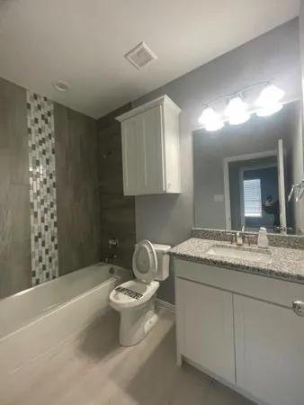 a spacious bathroom with a granite countertop sink a toilet and a bathtub