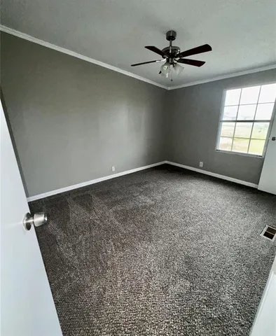 an empty room with a ceiling fan and window