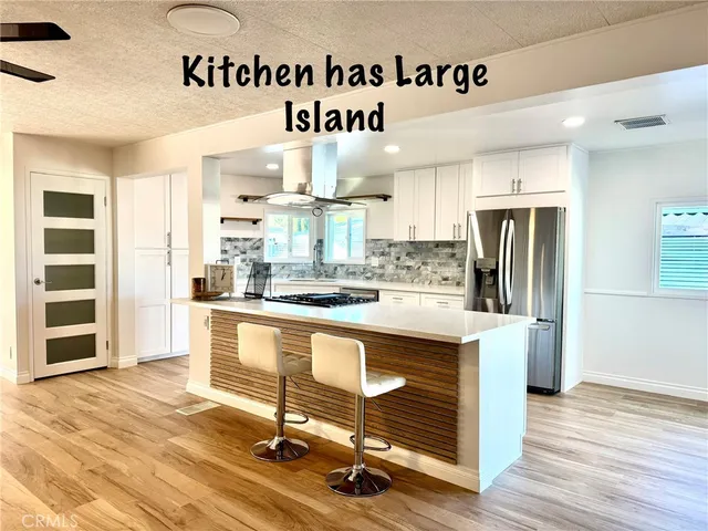 a kitchen with stainless steel appliances granite countertop a stove a sink dishwasher and a refrigerator with wooden floor