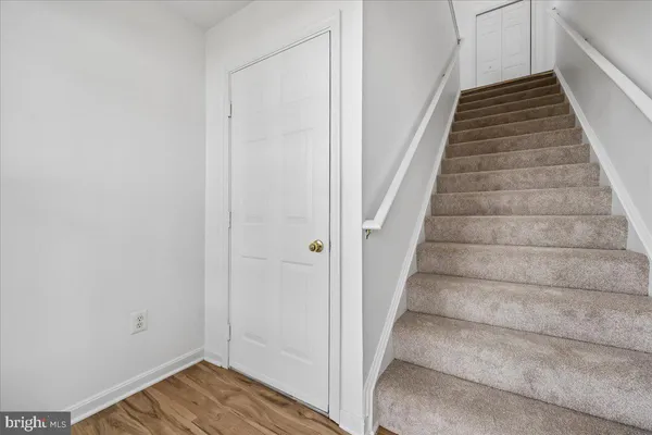 a view of staircase with wooden floor and white walls