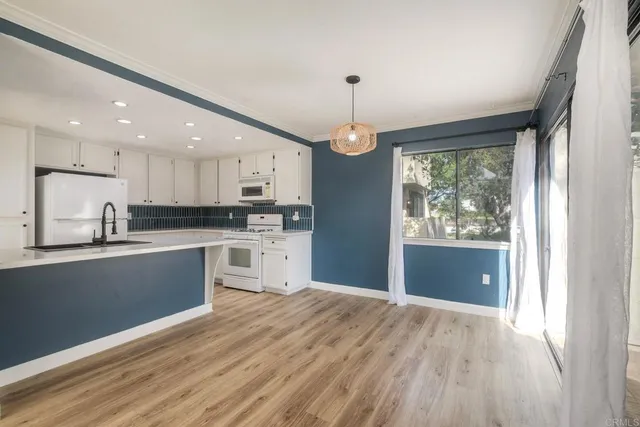 a open kitchen with granite countertop a refrigerator a stove a oven and white cabinets with wooden floor