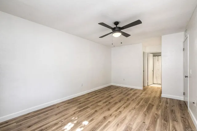 an empty room with wooden floor fan and windows