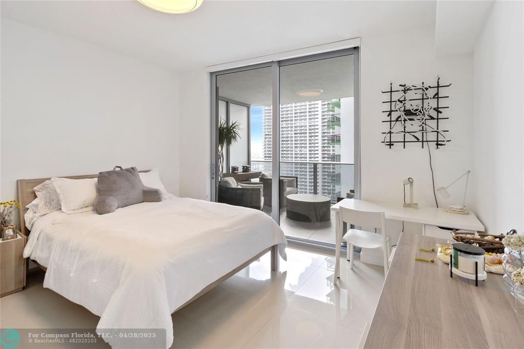 488 Northeast 18th Street, Unit 2010 Miami, FL 33132 - Photo 13 of 15 a spacious bedroom with a bed a table and chair