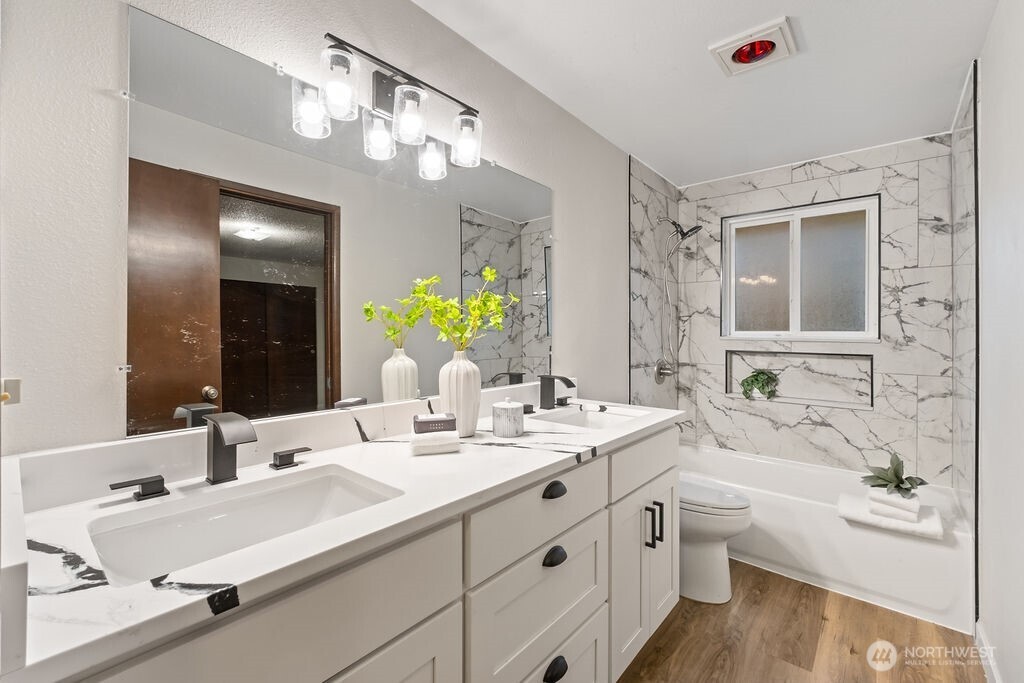 4813 208th Street East Spanaway, WA 98387 - Photo 19 of 39 a bathroom with a double vanity sink a large mirror and a bathtub