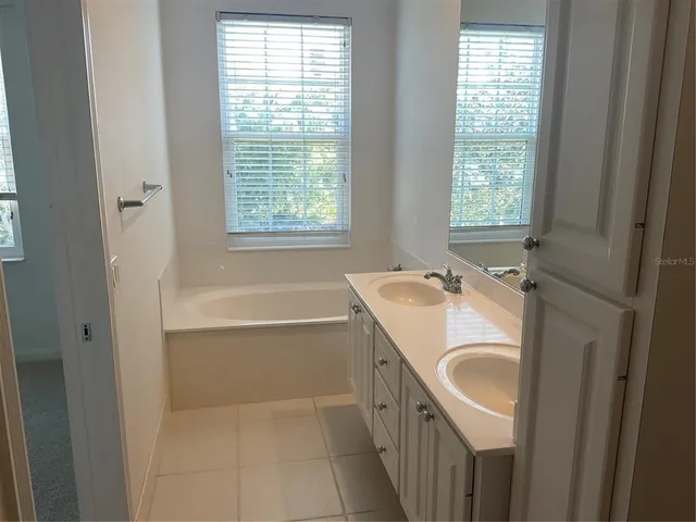 a bathroom with a granite countertop sink a bathtub window and mirror
