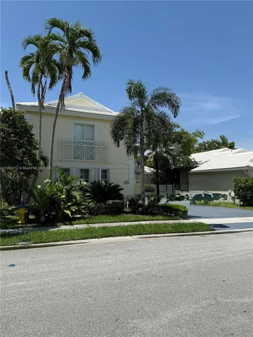 a palm tree sitting in front of a house with a yard