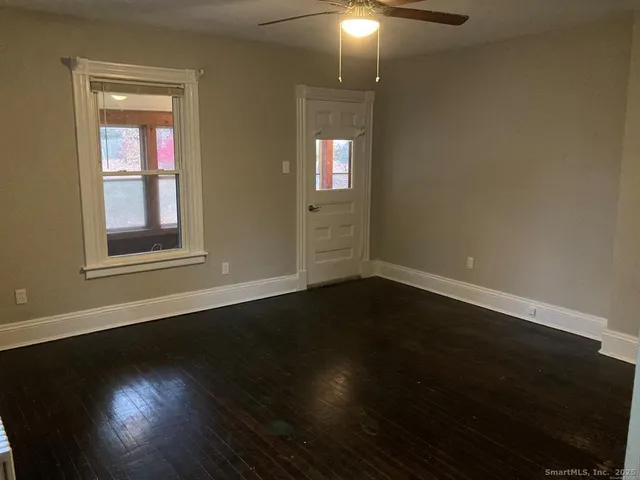 a view of an empty room with wooden floor and a window