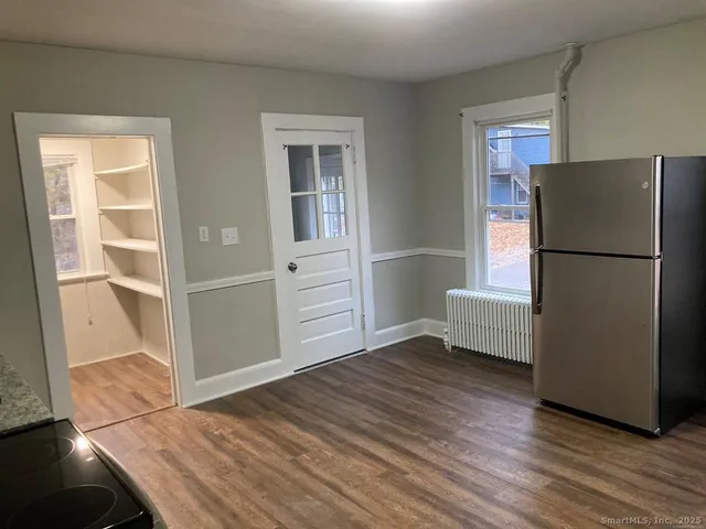a view of a livingroom with wooden floor and a refrigerator