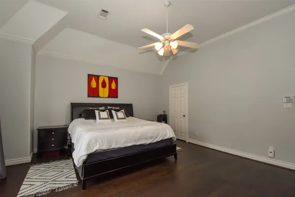 a bedroom with a bed and dresser with wooden floor