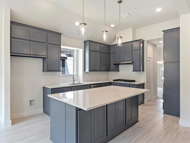 a large kitchen with a large center island a sink stainless steel appliances and cabinets
