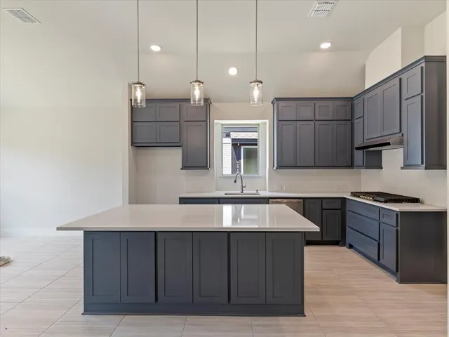 a large kitchen with kitchen island a large counter top stainless steel appliances and cabinets