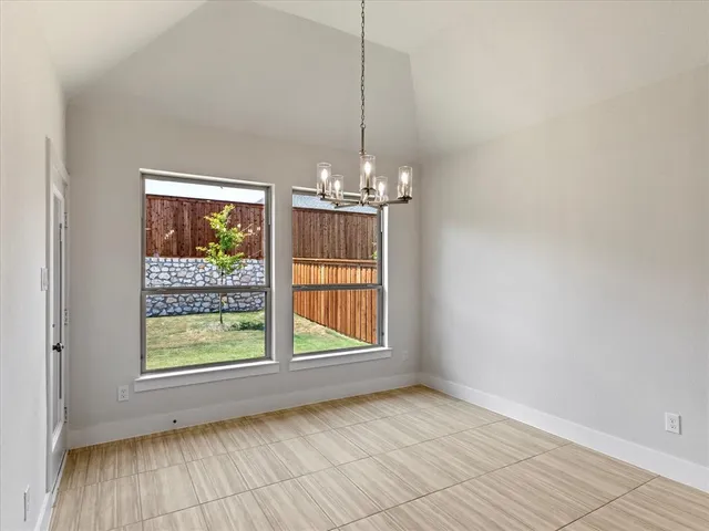 a view of an empty room with window and chandelier fan