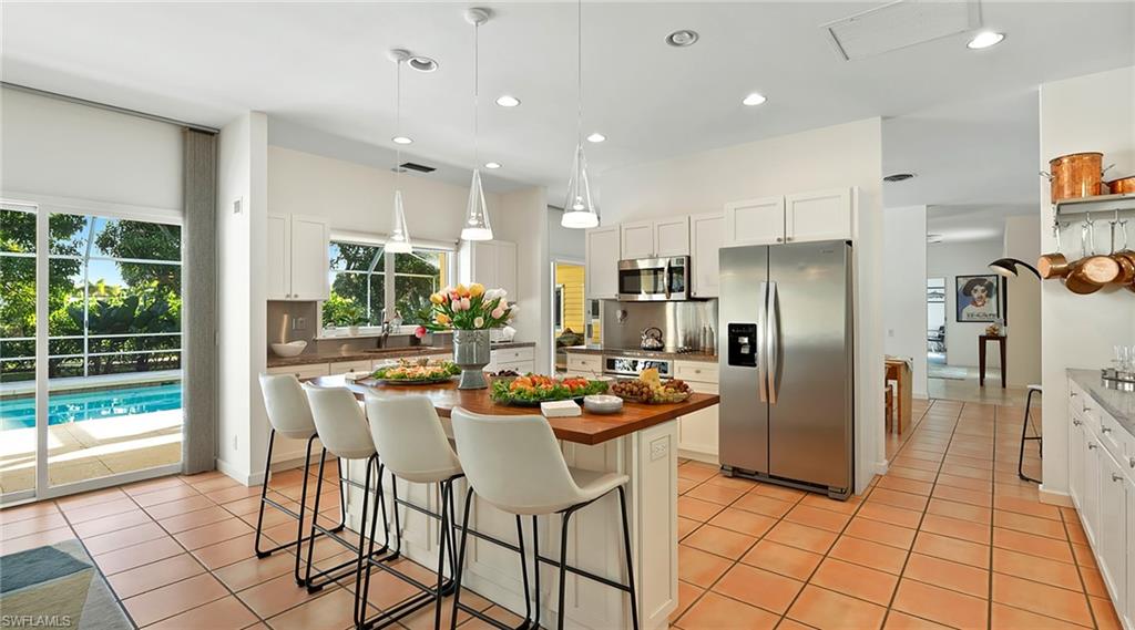 586 Yucca Road Naples, FL 34102 - Photo 8 of 26 Kitchen with appliances with stainless steel finishes, a kitchen bar, hanging light fixtures, a kitchen island, and white cabinetry