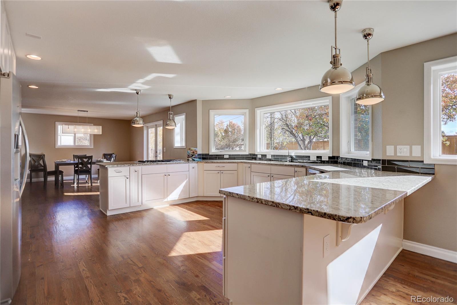3804 Simms Street Wheat Ridge, CO 80033 - Photo 12 of 40 a large kitchen with kitchen island lots of counter space a sink appliances and a large window