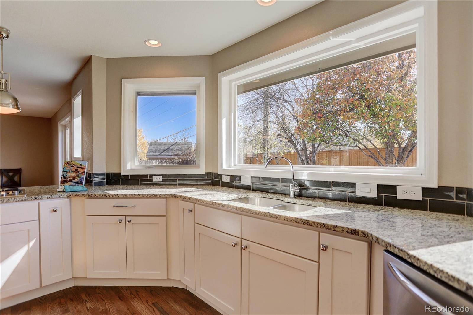 3804 Simms Street Wheat Ridge, CO 80033 - Photo 13 of 40 a kitchen with granite countertop white cabinets and a window