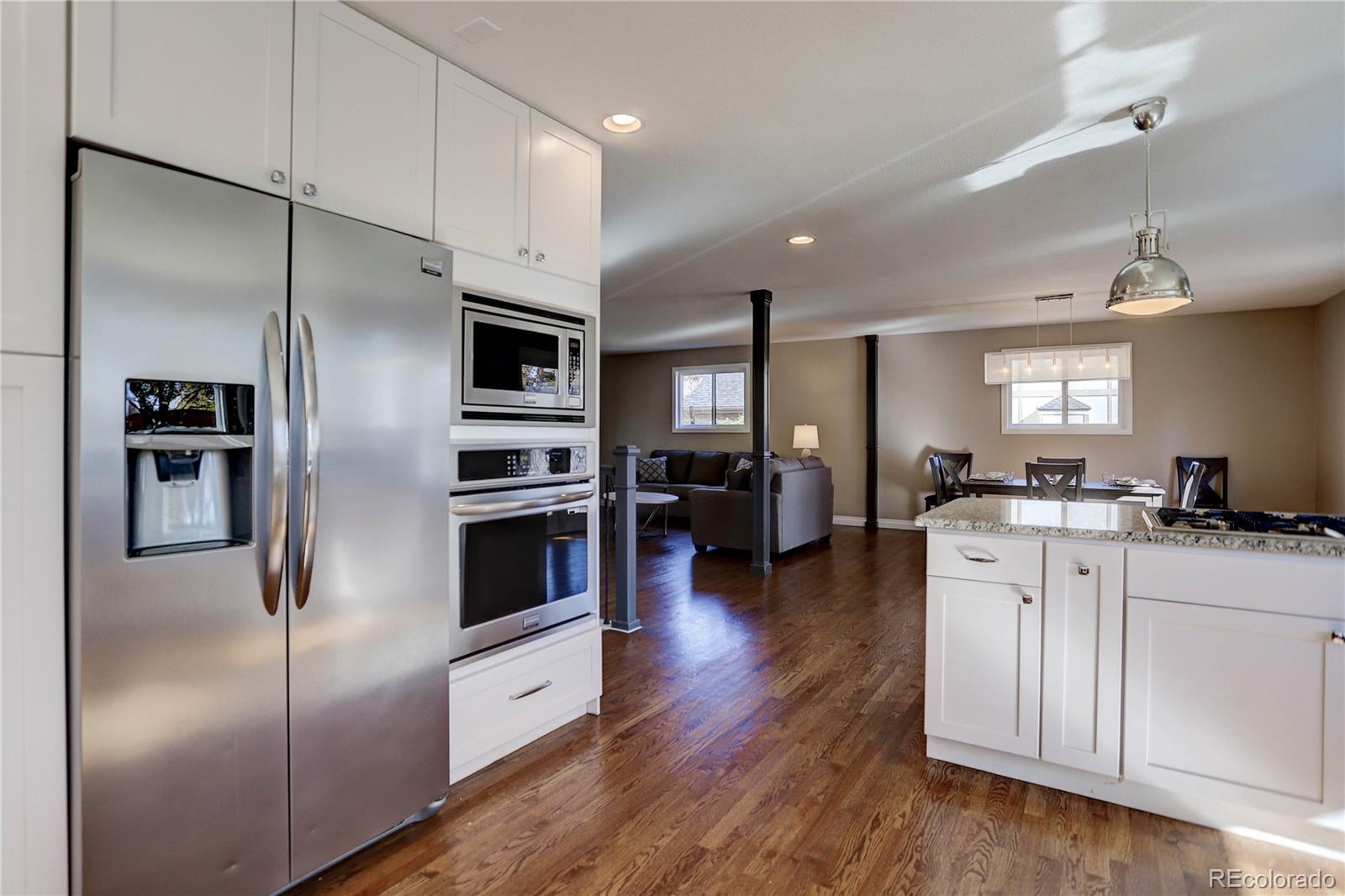 3804 Simms Street Wheat Ridge, CO 80033 - Photo 14 of 40 a kitchen with stainless steel appliances kitchen island granite countertop a refrigerator a stove a sink and white cabinets with wooden floor