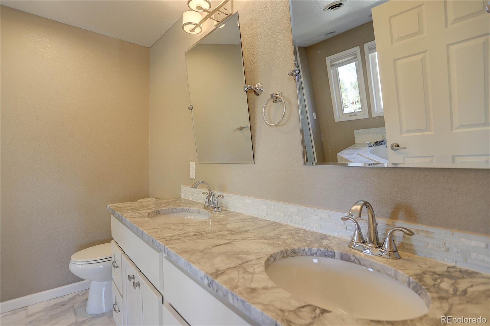 3804 Simms Street Wheat Ridge, CO 80033 - Photo 26 of 40 a bathroom with a granite countertop sink a toilet and a mirror