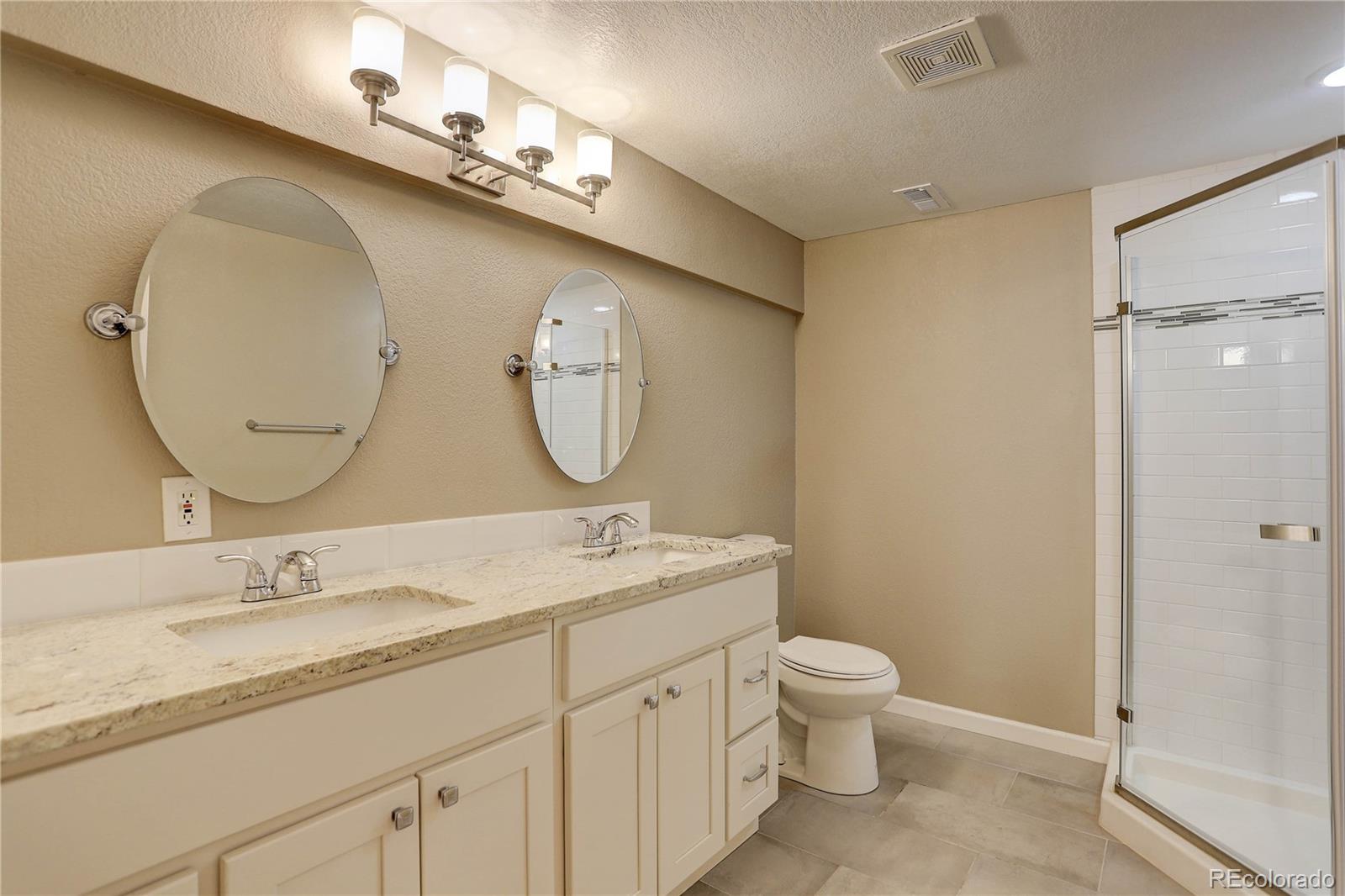 3804 Simms Street Wheat Ridge, CO 80033 - Photo 34 of 40 a bathroom with a granite countertop toilet a sink and a mirror