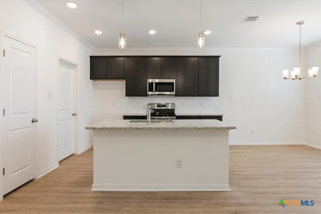 a kitchen with kitchen island stainless steel appliances a sink and a stove